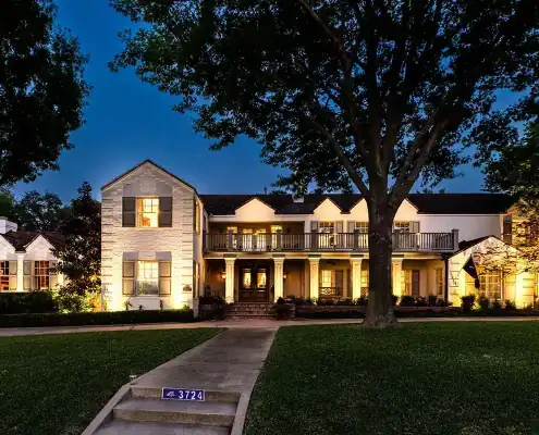 Large two-story colonial-style house lit at dusk, with columned porch, second-floor balcony, front walkway and big tree; curb number 3724.